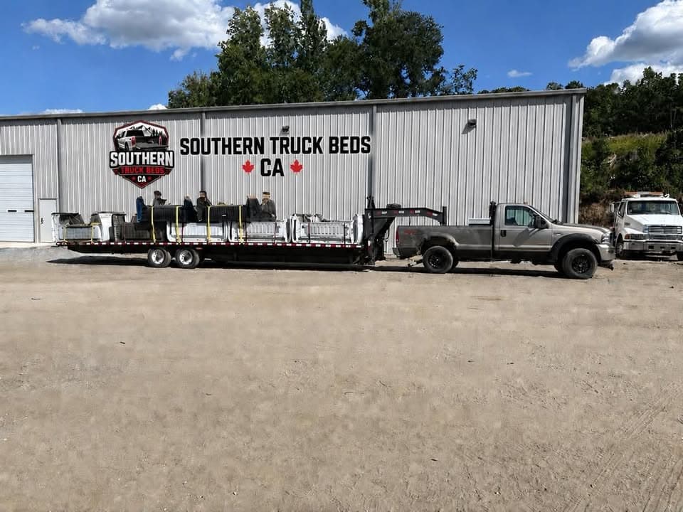 Southern Truck Beds CA warehouse with stacked pickup beds on a gooseneck trailer